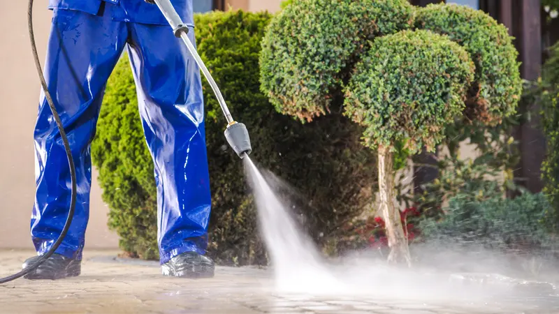 A person pressure washing concrete.