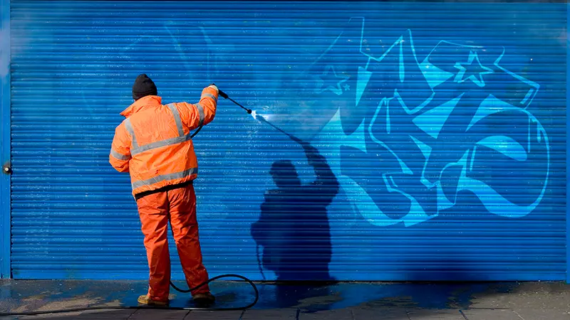 A person removing graffiti from a wall.