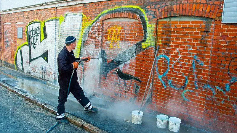 A person removing graffiti from a wall.