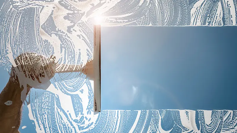 A person cleaning a window with a squeegee.
