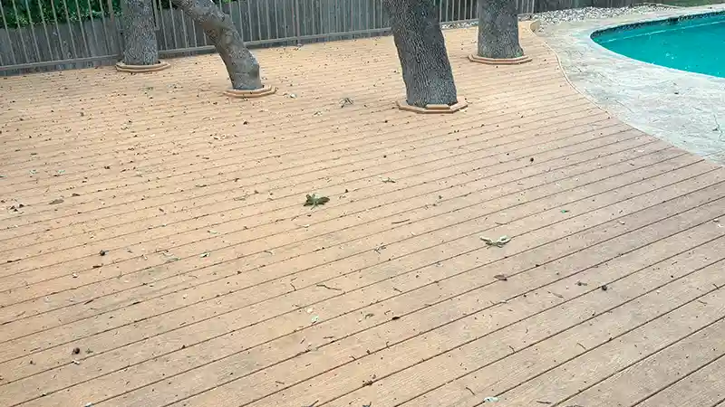 A dirty composite deck beside a pool.