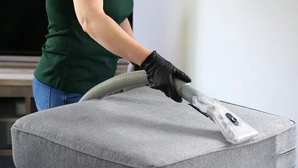 A woman vacuuming a couch.