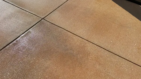 Concrete driveway with a faint, partially removed dark oil stain near the joint lines.