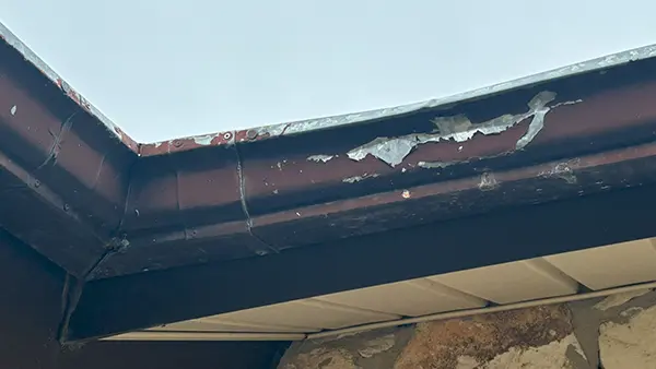 A rusted gutter with holes that's leaking.