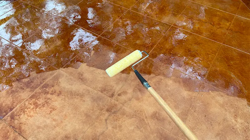A glossy sealer being applied to stained concrete in San Antonio.