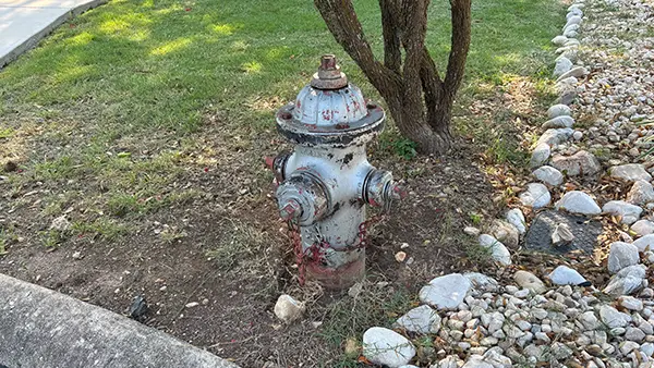 A silver fire hydrant that's missing its paint.